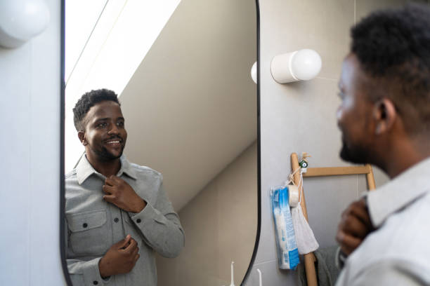 istock Young man looking himself in mirror in bathroom 2162202739