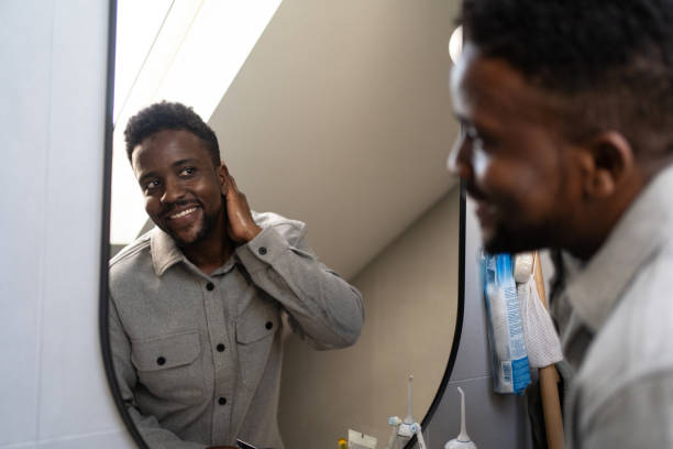 istock Young man looking himself in mirror in bathroom 2162202846