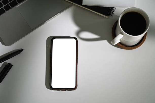 istock Smartphone with empty screen, coffee cup and laptop on white table. Top view, Flat lay 2162203443