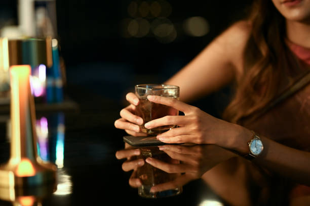 Close up shot young woman relaxing with glass of whiskey at bar counter stock photo