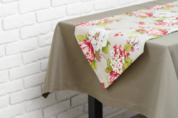 istock Floral Table Runner on a Beige Tablecloth Against a White Brick Wall 2162204101