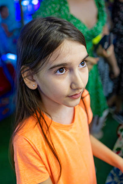 A charming portrait of a young girl in an orange t-shirt, enjoying a leisurely walk.