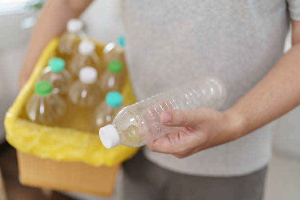 istock Home recycle eco green zero concept Man throwing empty plastic bottle in recycling bin with yellow garbage bags at home 2162210882