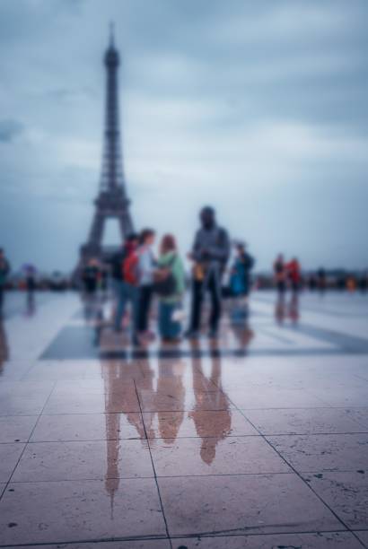 istock The Eiffel Tower is reflected in a wet Parisian square, blurred figures pass by. 2162211366
