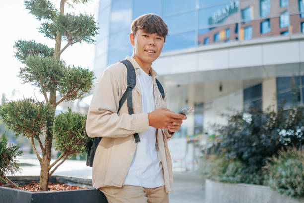 istock Satisfied Young Man with Smartphone looking at camera in Outdoor Conversation 2162212654