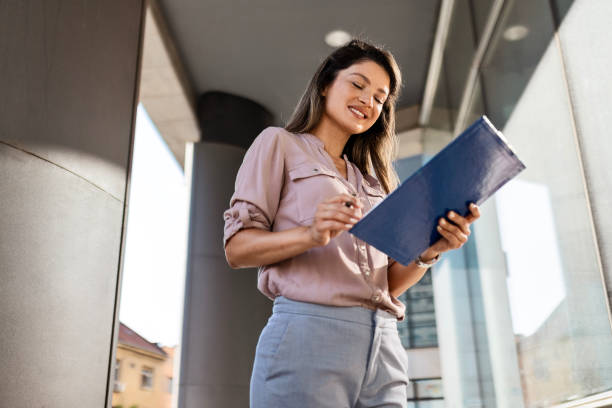 istock Woman with Clipboard by Office Building 2162215345