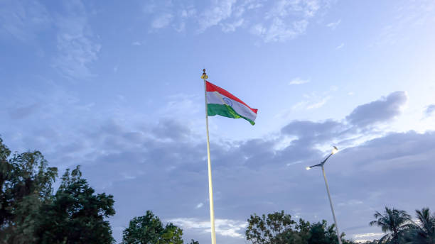 istock An India flag on a white pole, trees and blue sky behind it. 2162216659