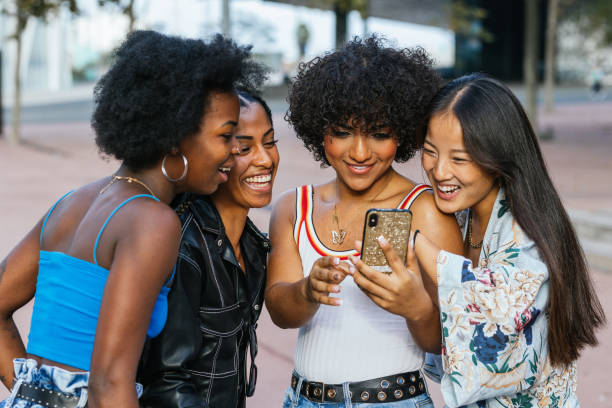 istock Multi-ethnic friends standing together using phone in the street 2162223312