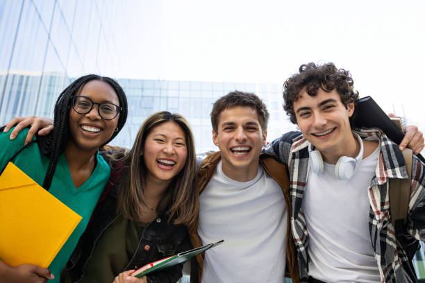 istock Happy college students embracing, laughing and having fun after class in front of university building looking at camera. 2162226705