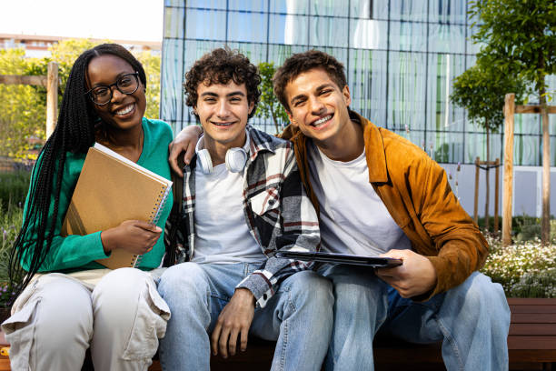 istock Multiracial college students sitting on campus bench looking at camera. Copy space. 2162226706