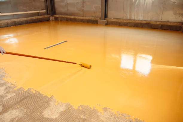 istock Construction worker applying epoxy resin with a roller in an industrial building 2162227379