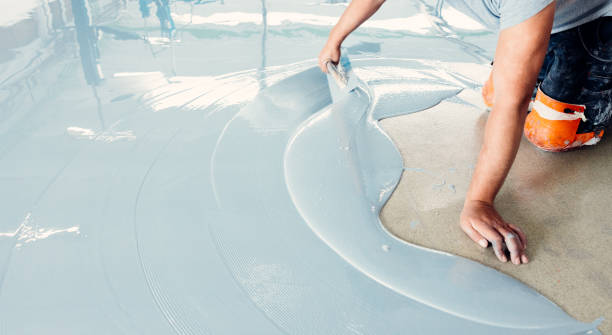 istock Construction worker spreading self-leveling concrete on the floor 2162227534