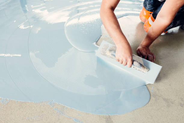 istock Construction worker spreading self-leveling concrete on the floor using a trowel 2162227550