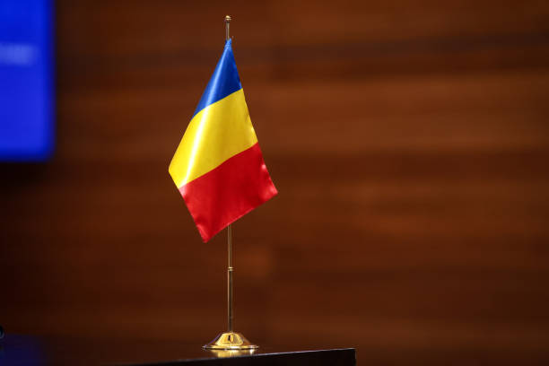 istock Romanian flag on a golden small pole on a wooden table during a diplomatic event. 2162227799