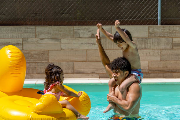 istock Father and son play in pool while daughter sits on inflatable duck, enjoying summer day. 2162228698