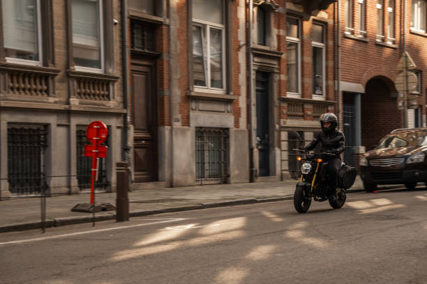 Full length shot of female biker in leather jacket riding motorcycle through the city