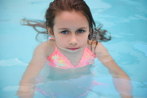 Happy little girl with inflatable toy ring float in swimming pool. Little preschool child learning to swim and dive in outdoor pool of hotel resort. Healthy sport activity and fun for children