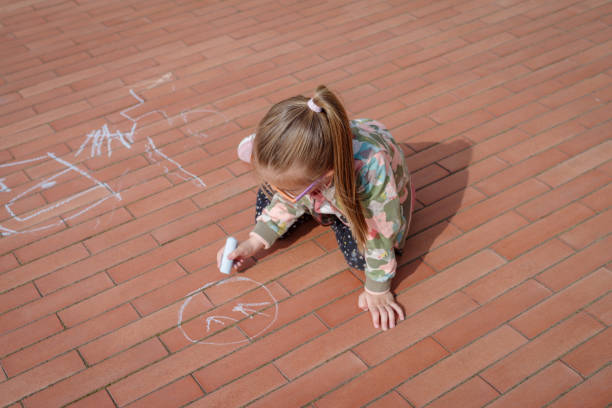 istock Girl scribbling in colourful chalk on pavement 2162236009