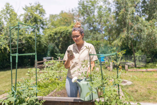 istock A woman uses a mobile phone while taking a break from watering the garden 2162237161