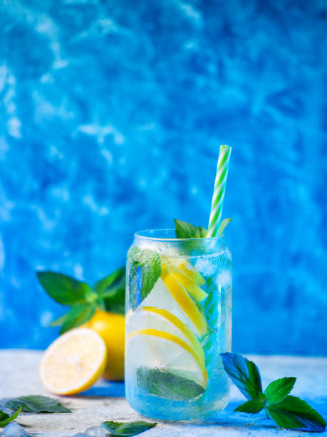 istock Refreshing summer mojito cocktail with lemon slices and mint. Blue background 2162240544
