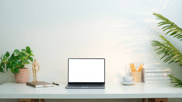 istock Front view laptop , books and cup of coffee on white table with warm light. Blank screen for your advertising text message. 2162240546