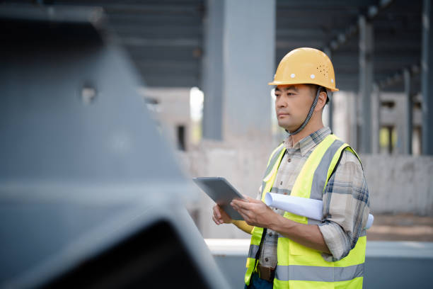 istock Middle-aged male construction technician wearing work helmet and protective workwear, working at a construction site 2162241871