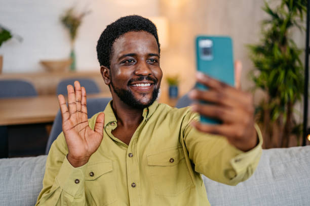 istock Young Man Having A Video Call On The Phone While Sitting On The Sofa At Home 2162243656