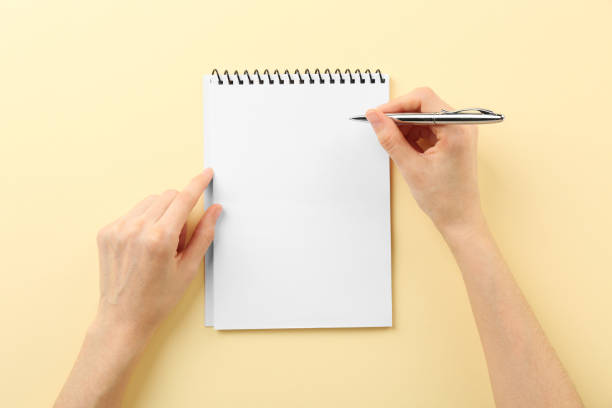istock Woman writing in notebook on beige background, top view 2162245791