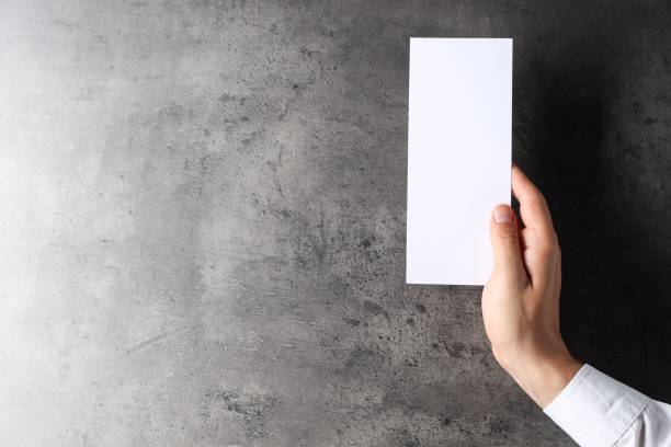 istock Man holding blank card at black textured table, top view. Mockup for design 2162246620