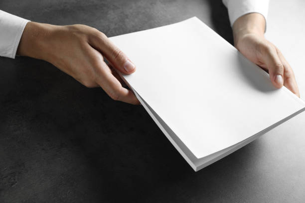 istock Man holding blank notebook at black textured table, closeup. Mockup for design 2162246653