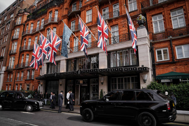Union Jack Flag (Union Flag) on Claridge's Hotel Facade, Brook Street London W1, England, United Kingdom London, England, United Kingdom (UK), Britain, Europe – On July 12, 2024: A daytime shot capturing the Union Jack flag, British Union Flag - the flag of the United Kingdom, displayed on the elegant facade of Claridge's Hotel on Brook Street, located on Brook Street in the prestigious London W1 area; black cabs, people, and luxury cars, & pedestrians create a lively atmosphere. city of london flag stock pictures, royalty-free photos & images