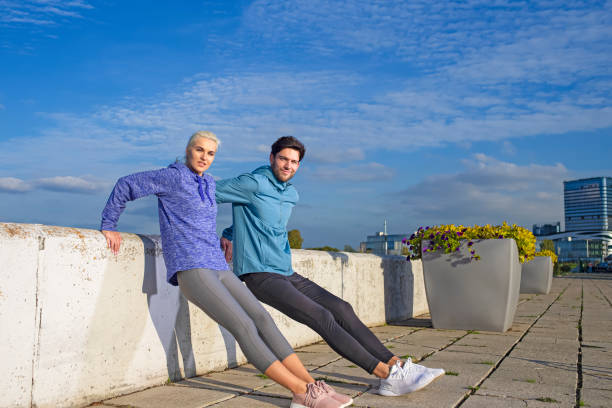 Positive Caucasian Runners Athletes Relaxing During Training Together And Smiling As Fitness Exercise Outside While Training Outdoor Process. Horizontal Orientation