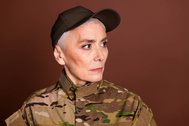istock Photo of attractive confident elderly lady dressed camo uniform looking empty space isolated brown color background 2162256440