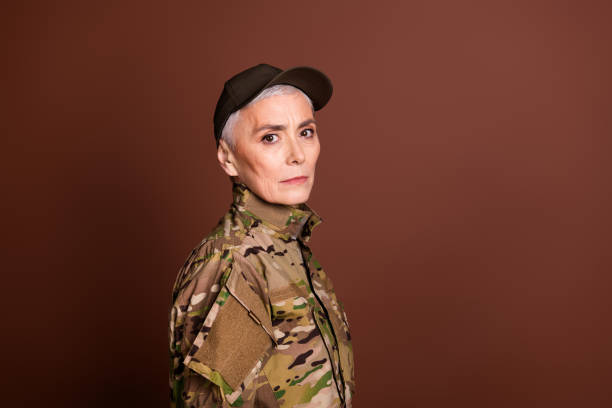 istock Photo of strong serious elderly lady dressed camo uniform support country empty space isolated brown color background 2162256446