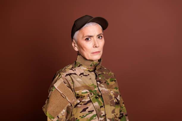 istock Photo of sserious confident elderly lady dressed camo uniform empty space isolated brown color background 2162256558