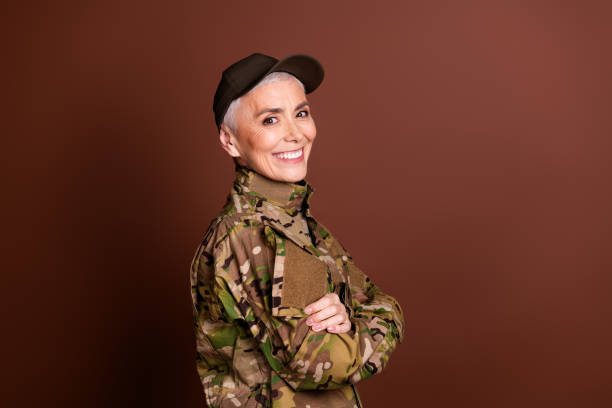istock Photo of cheerful confident elderly lady dressed camo uniform arms folded empty space isolated brown color background 2162256595