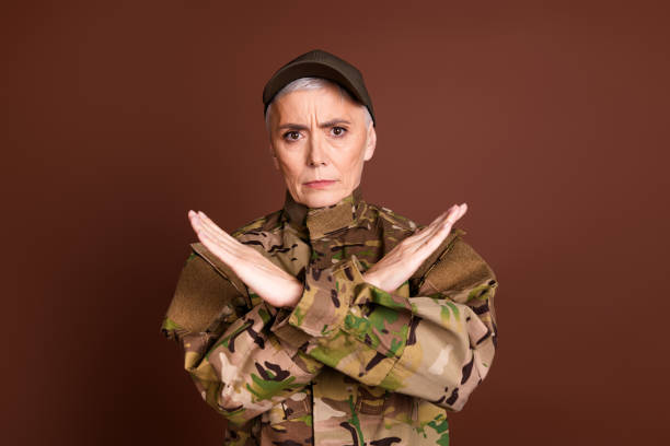 istock Photo of strong serious elderly lady dressed camo uniform fighting enemies empty space isolated brown color background 2162256601