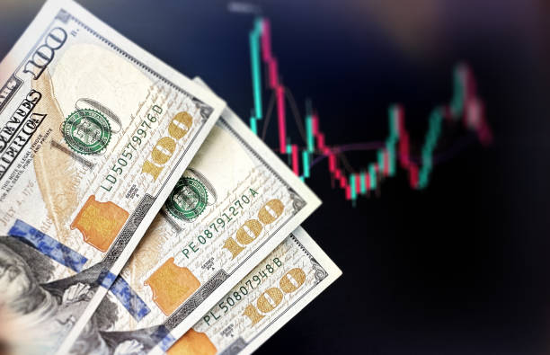 istock Man Hand Holding 100 Dollar Banknotes with Finance Graph in Background 2162257514