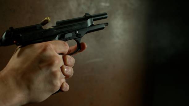 istock Man Shooting a Pistol on Dark Background 2162260602