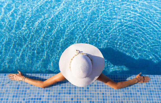 istock Woman in hat relaxing at the pool 2162260764
