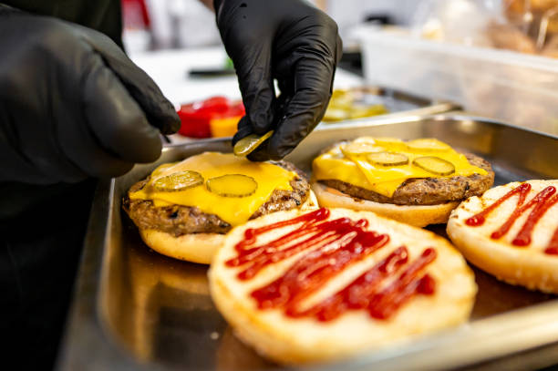 istock Close-up of hands assembling a freshly prepared cheeseburger with lettuce, tomato, and sesame bun, showcasing fast food preparation 2162261782