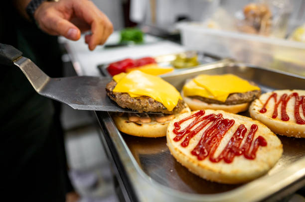 istock Close-up of hands assembling a freshly prepared cheeseburger with lettuce, tomato, and sesame bun, showcasing fast food preparation 2162261797