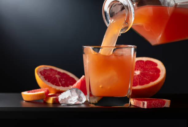 istock Glass of grapefruit juice with ice on a black background. 2162267396