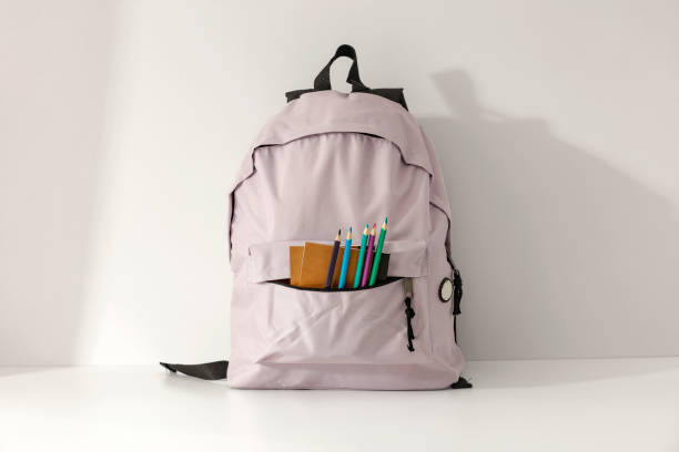 istock School backpack and school stuff with space for products on light grey wall background. 2162274143