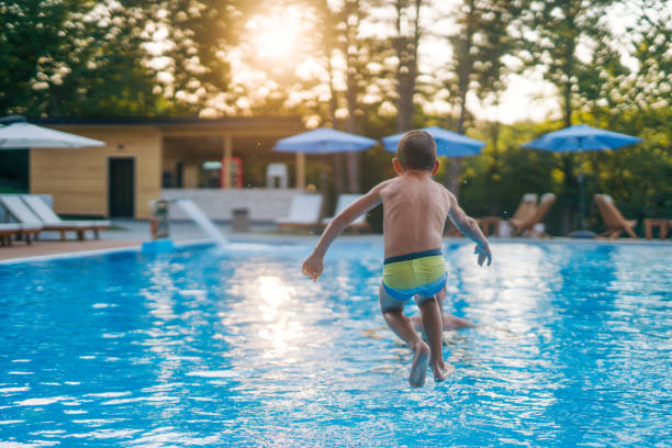 istock The boy jumps into the pool while his dad waits in the pool. 2162282422