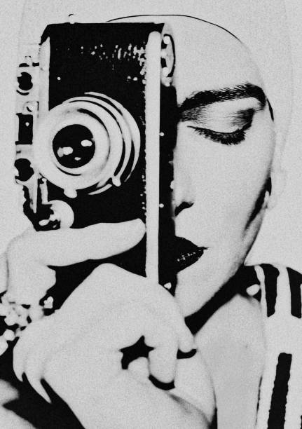 The photographer. Portrait of a fashion model with a camera. She is holding the camera in front of her face and has her eyes closed. An iconic photo. black and white portrait photographers stock pictures, royalty-free photos & images
