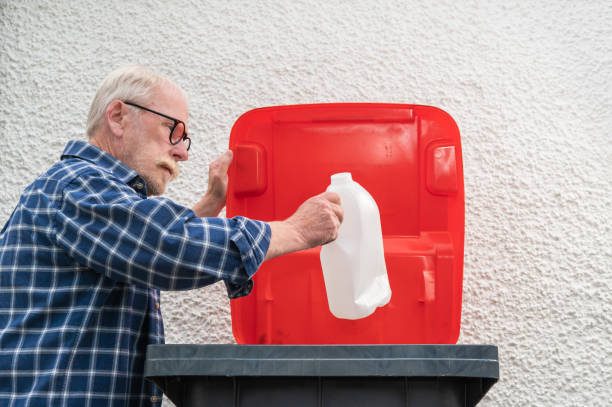 Person throwing garbage into the trash bag inside a business while working, dressed in work uniform