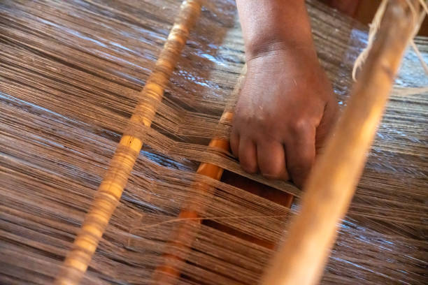 worker hands detail with traditional natural silk making machine strings