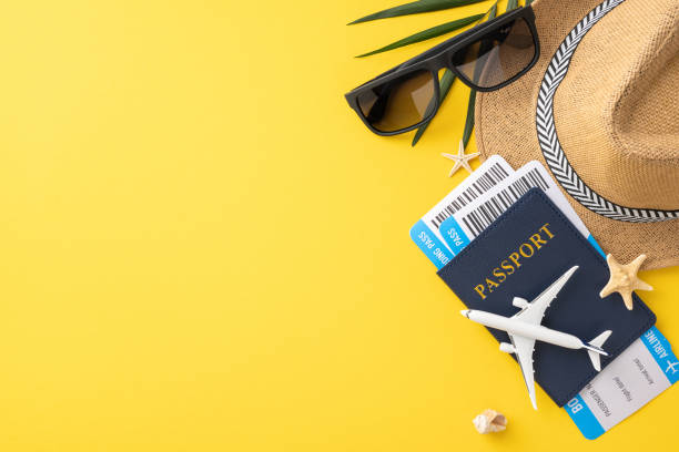 istock Travel essentials including a passport, boarding passes, sunglasses, and a hat arranged on a yellow background reflecting a summer vacation vibe 2162287886