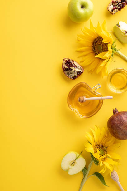 istock Festive Rosh Hashanah composition featuring honey, apples, sunflowers, and pomegranate on a vibrant yellow vertical background 2162287974
